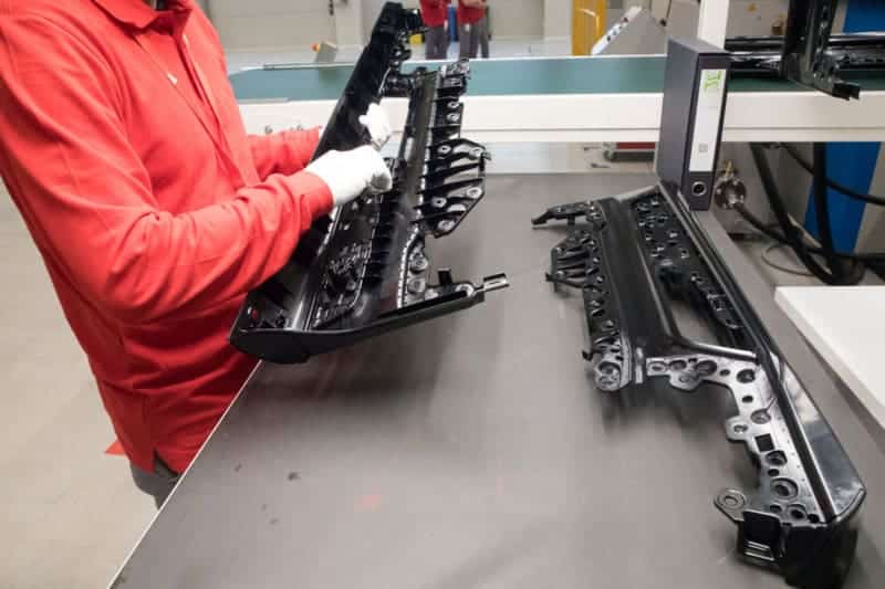 Worker inspecting black automotive parts on table