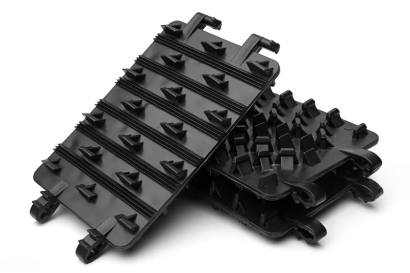 Stacked black plastic trays with protruding structures