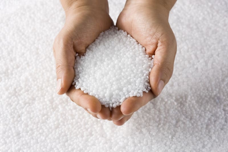 Hands holding white plastic pellets