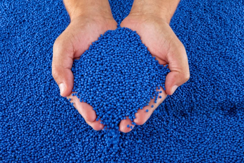 Hands holding blue plastic pellets