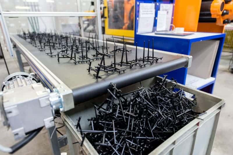 Black plastic parts on conveyor in production line