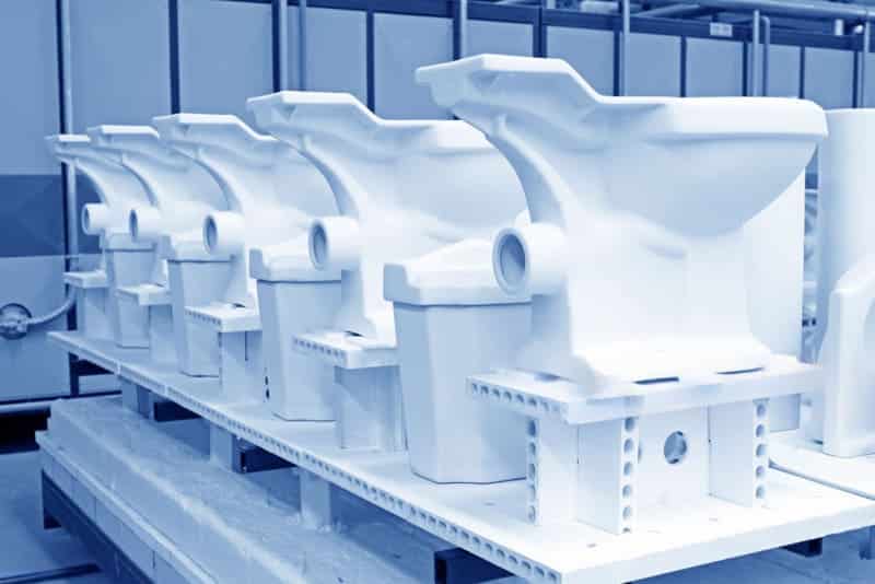 Row of white toilet molds in factory setting