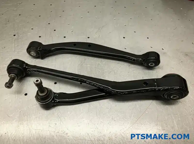 Black custom suspension arms with joints on a workbench